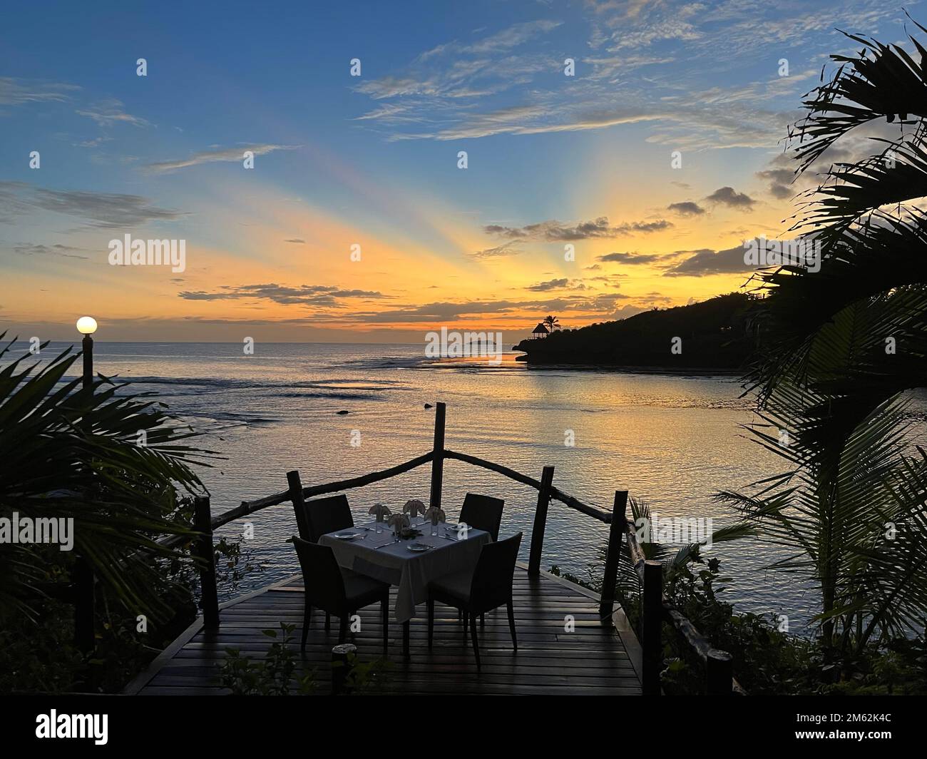 Romantic dinner table in front of a tropical sunset Stock Photo