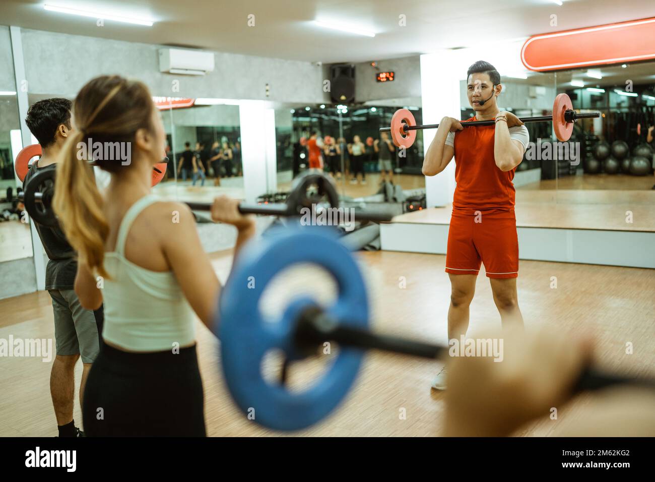 selective focus of instructor lifting barbell in front of chest Stock Photo