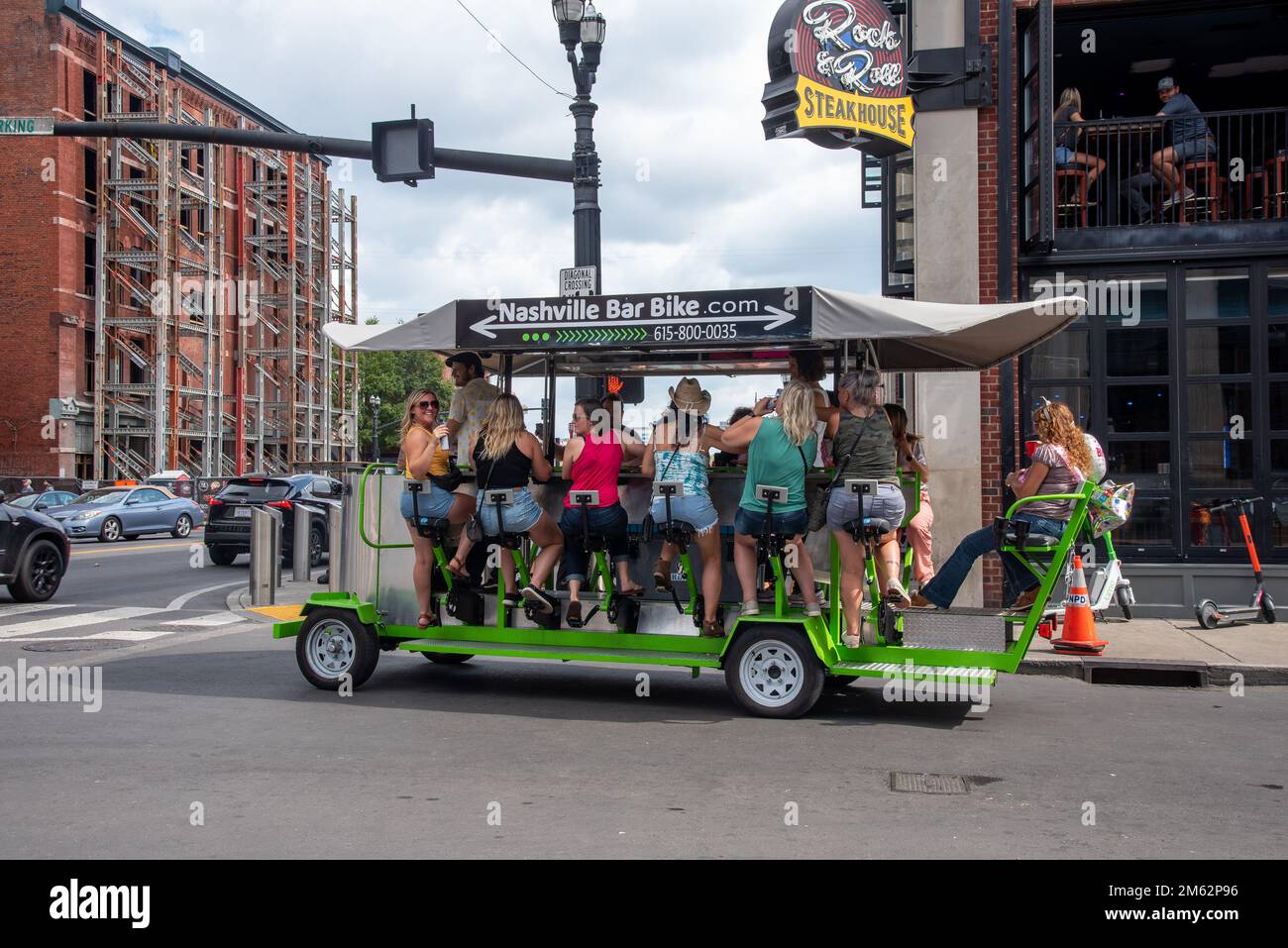 Women in blue jean shorts tour downtown Nashville on a party bar bike, a multi-passenger human-powered vehicle. Stock Photo