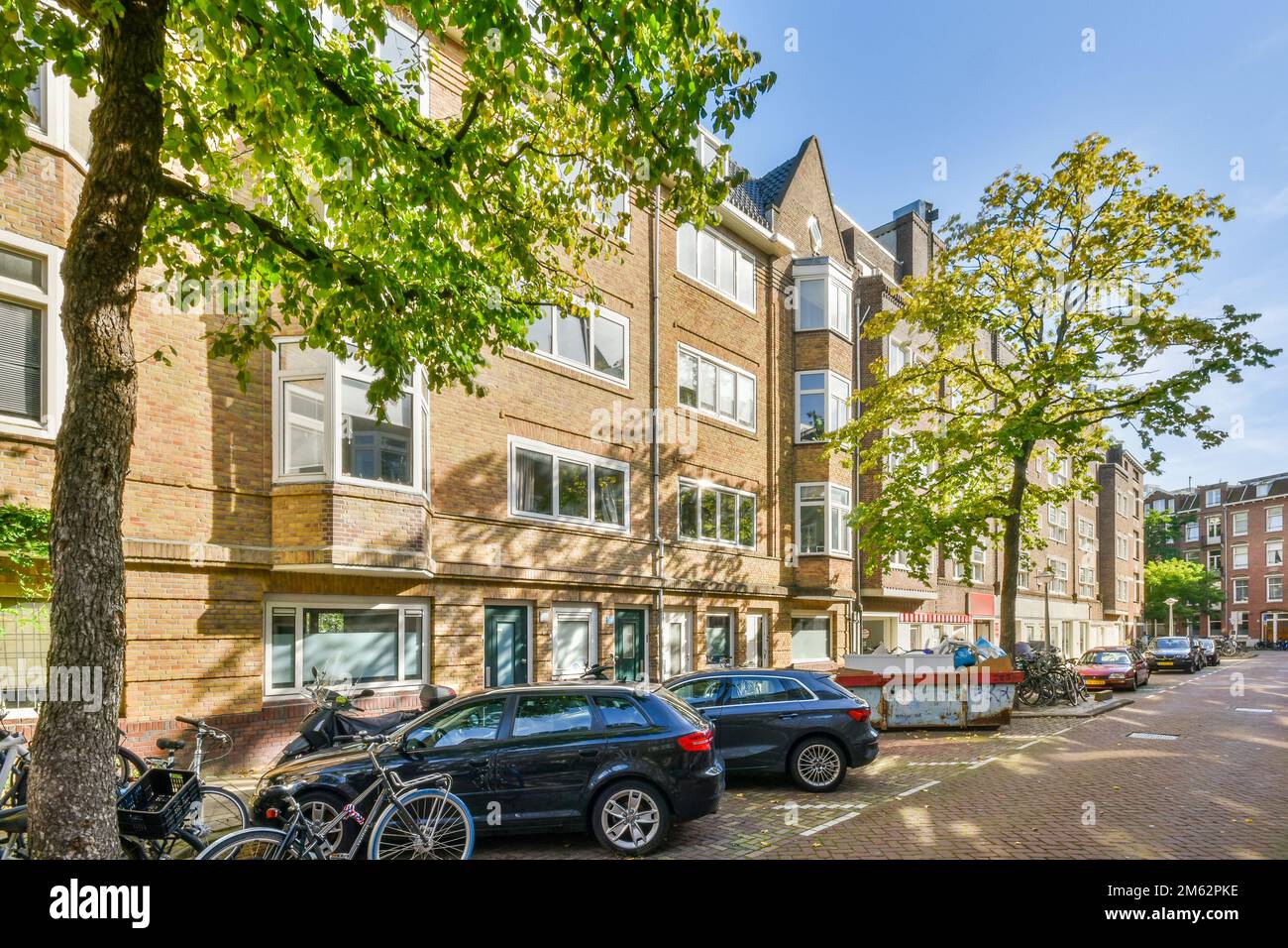 a city street with cars parked on the curbs and trees in front of some ...