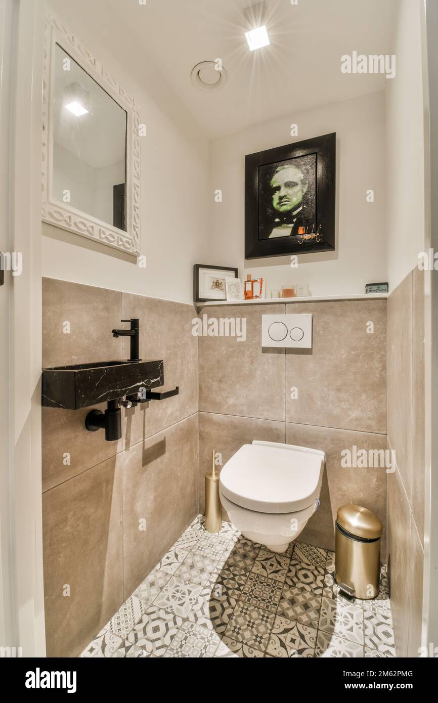 a bathroom with a toilet and mirror on the wall next to it is an image of a man's face Stock Photo