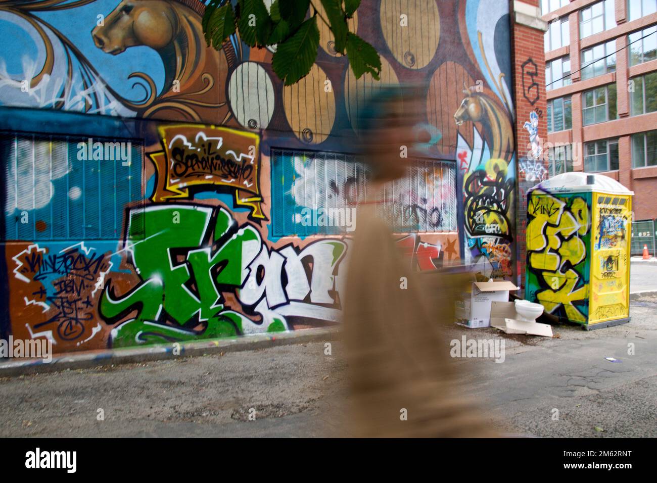 Blurred motion of a woman walking with the graffiti background. Stock Photo