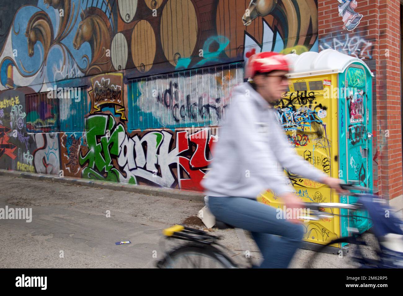 Blurred motion of a man riding a bicycle with the graffiti background. Stock Photo