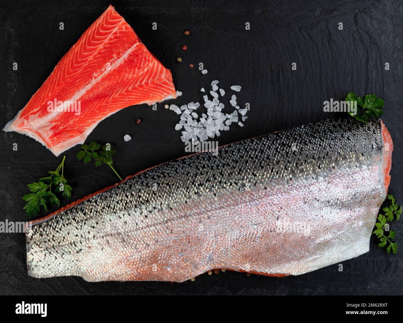 Two Salmon trout fillet, skin side up and down, on natural dark stone