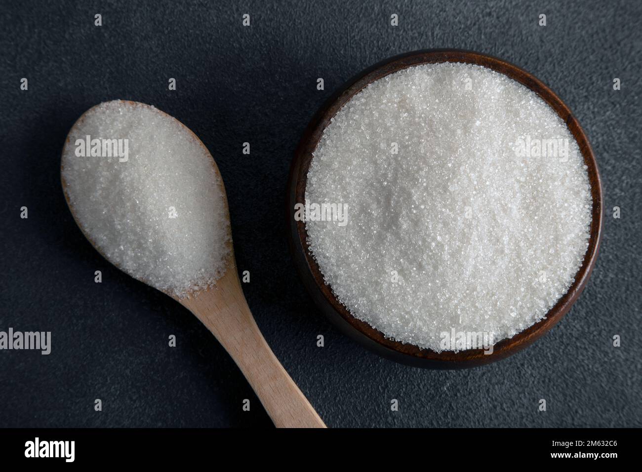 Granulated sugar in bowl on dark background Stock Photo