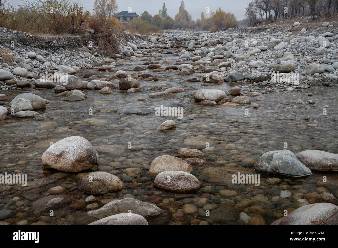 Slow and not deep mountain river with rounded stones Stock Photo