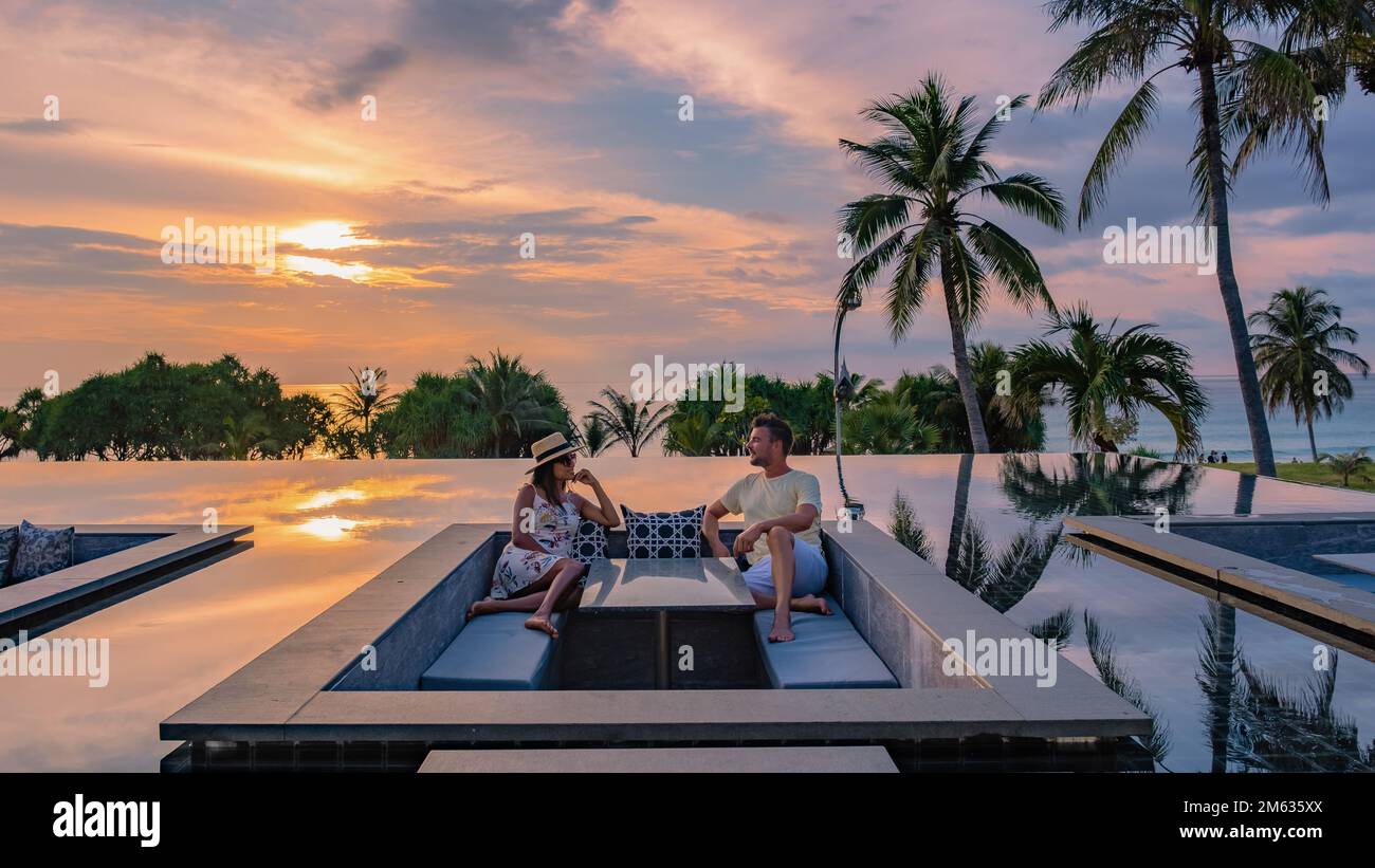 couple watching the sunset in an infinity pool on a luxury vacation in ...