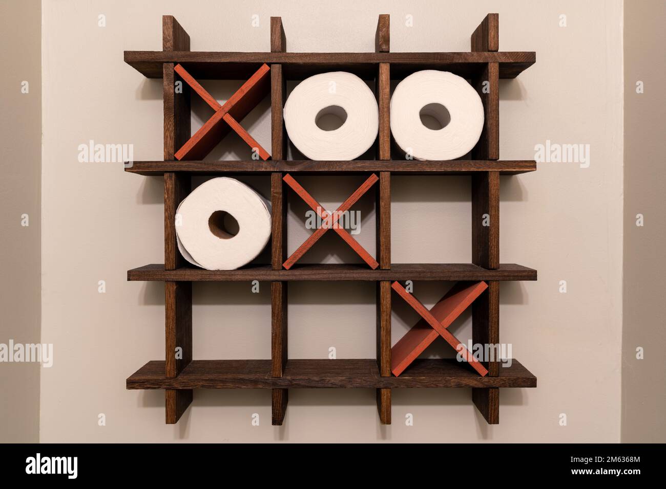 A Tic-Tac-Toe wooden shelf for rolls of toilet paper. Toilet decoration. Noughts and crosses, Xs and Os. Stock Photo