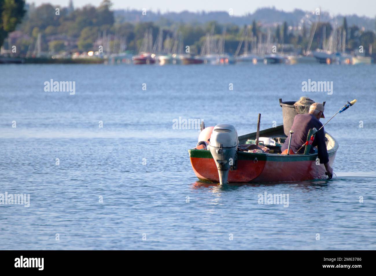 Fisherman on a small boat casting his nets for fishing Stock Photo Alamy
