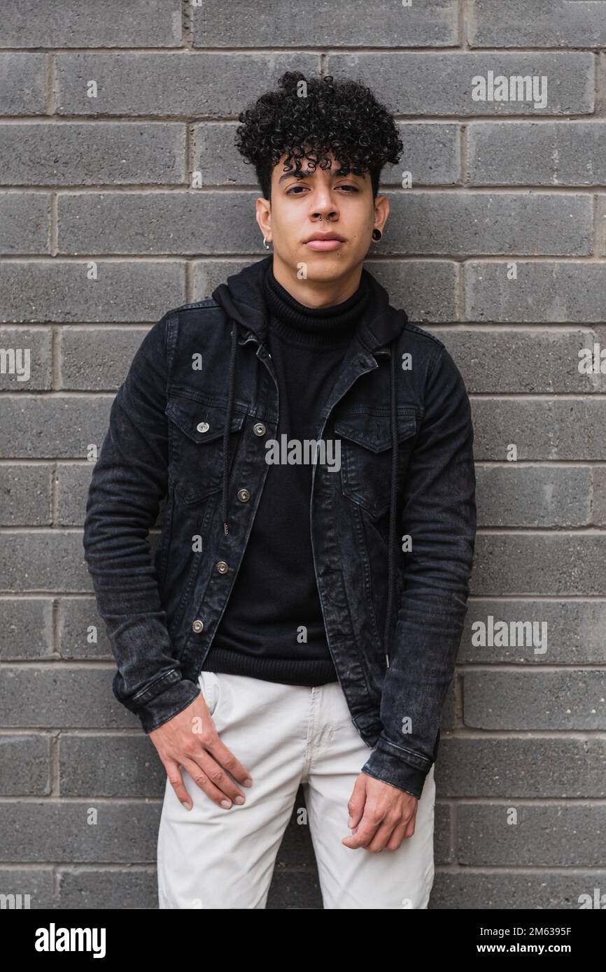 Portrait of young ethnic curly haired man in casual outfit standing with  hand in pocket looking at camera Stock Photo - Alamy