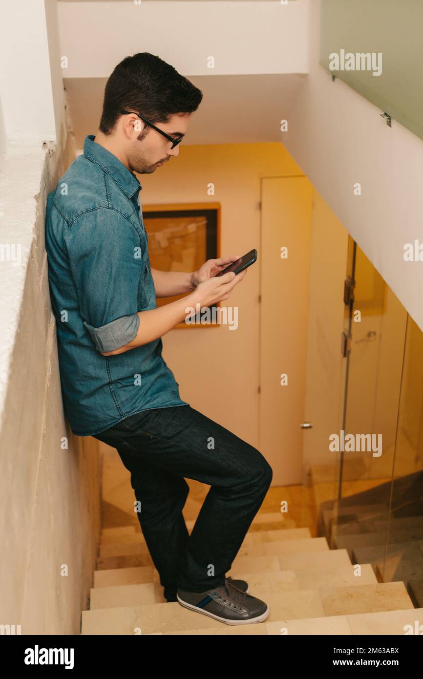 Young Man standing on a Ladder Using his Mobile Phone Stock Photo