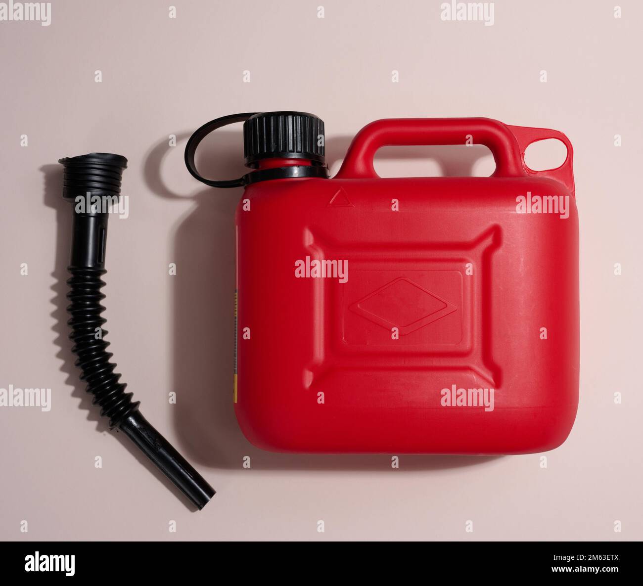 Red plastic canister for liquid fuels and lubricants on a beige