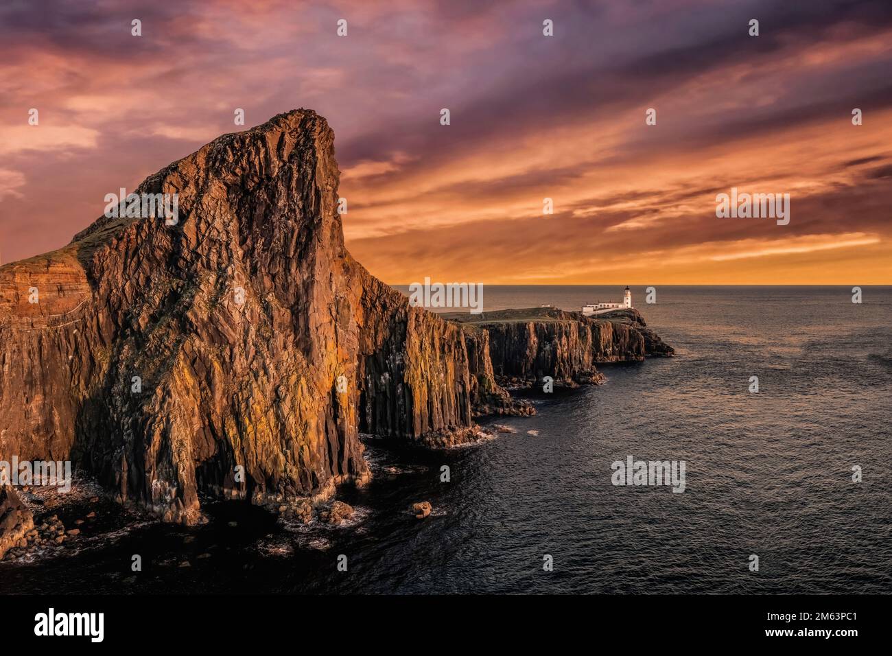 Neist Point Lighthouse in the Isle of Skye in Scottish Highlands, outcrop in the Atlantic Ocean. Aerial view at sunset looking onto the Light House Stock Photo