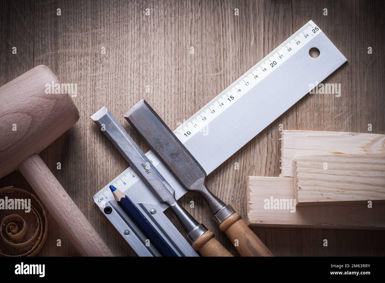 Wooden bricks hammer curled up planning chips firmer chisels square ruler pencil on wood board construction concept. Stock Photo