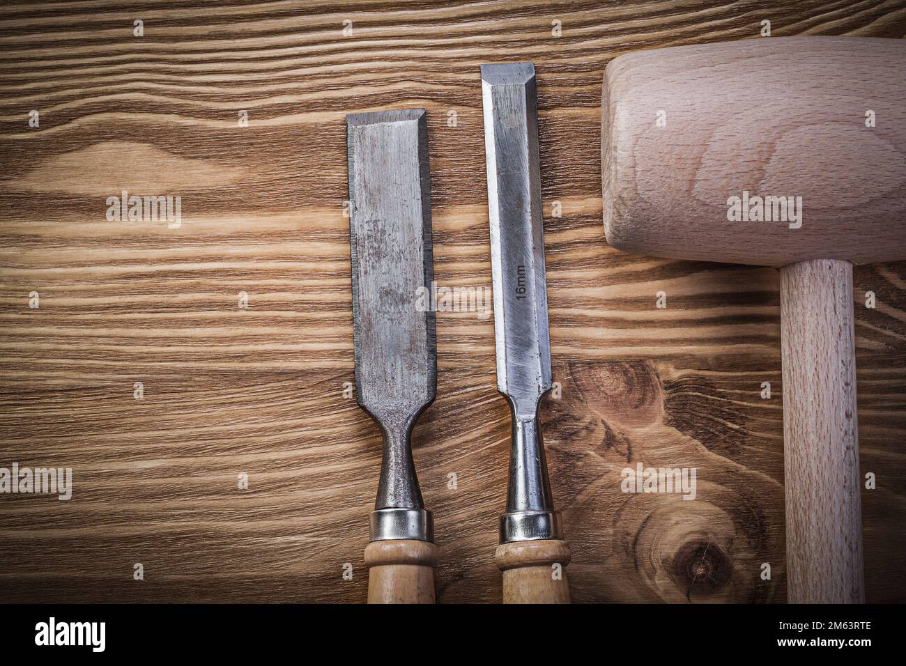 Wooden hammer firmer chisels on vintage wood board construction concept. Stock Photo