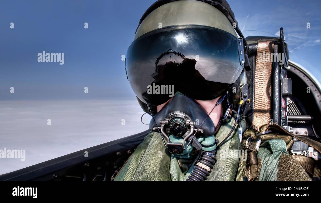 Pilot in the cockpit in an ejector seat wearing helmet, visor and oxygen mask flying high above the clouds Top Gun style fighter pilot black visor Stock Photo