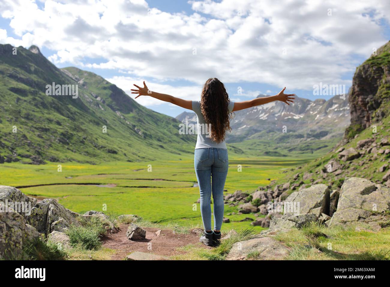 Back view portrait of an ecotourist celebrating summer vacation in the mountain outstretching arms Stock Photo