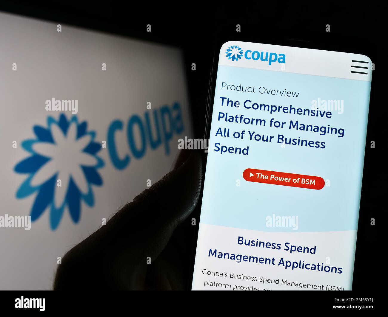 Person holding cellphone with webpage of spend management company Coupa Software Inc. on screen with logo. Focus on center of phone display. Stock Photo