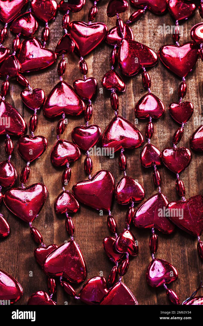 background red valentines beads garland on old wooden board Stock
