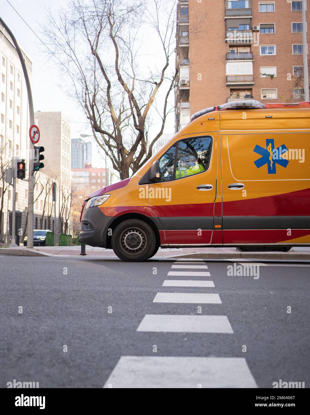 orange and red ambulance driving on green traffic light in Madrid city