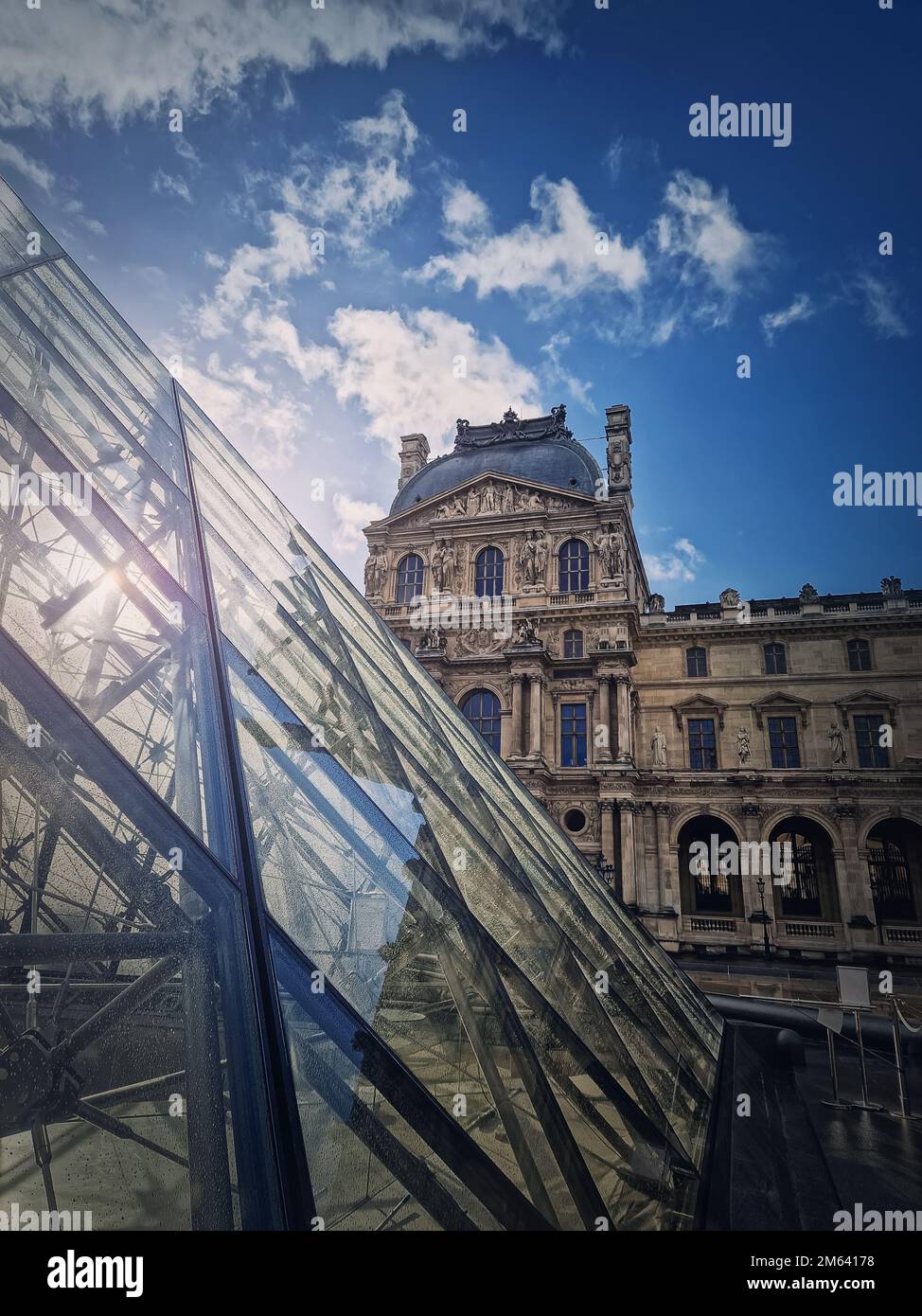 Outdoors view to the Louvre Museum in Paris, France. Vertical shot of the historical palace building with the modern glass pyramid in front Stock Photo