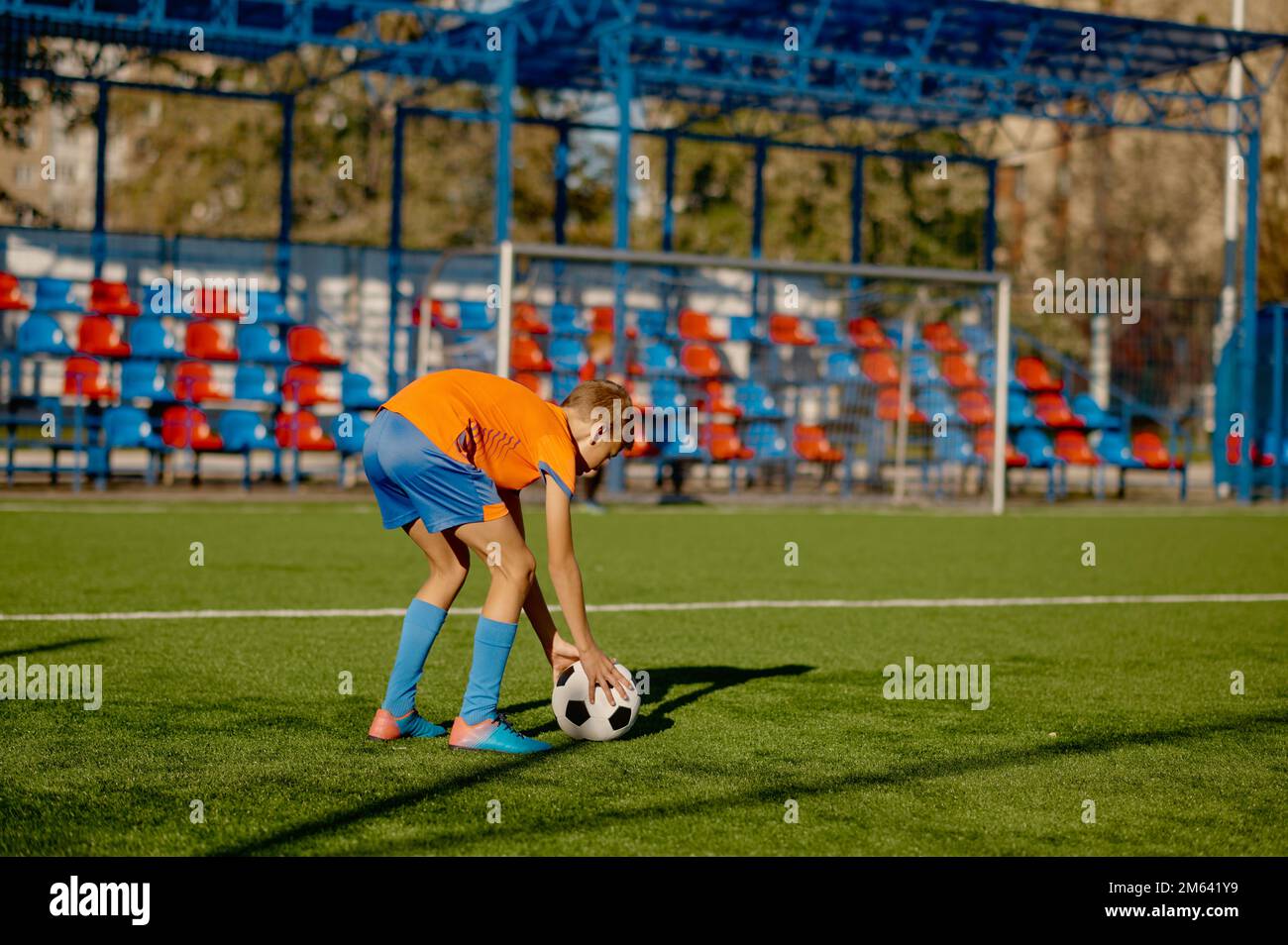 Junior football player placing ball on grass field for free kick or