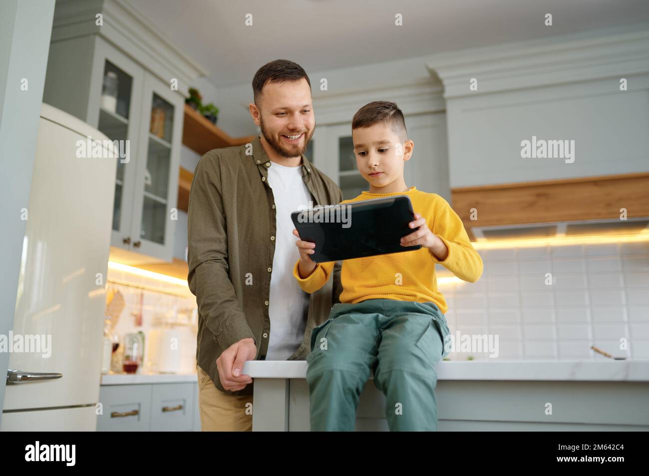 Father with son using digital tablet together at home kitchen Stock Photo