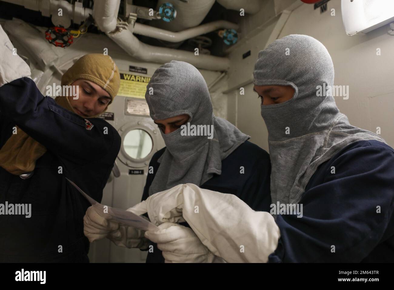 NORTH ATLANTIC OCEAN (March 31, 2022) Operations Specialist Seaman Aldwin Zarate, right, Gas Turbine Systems Technician (Electrical) Miguel Santana, middle, and Damage Controlman 3rd Class Jeffrey Allen read a material condition zebra card during a general quarters drill aboard the Arleigh Burke-class guided-missile destroyer USS Roosevelt (DDG 80), March 31, 2022. Roosevelt, forward-deployed to Rota, Spain, is on its third patrol in the U.S. Sixth Fleet area of operations in support of regional allies and partners and U.S. national security interests in Europe and Africa. Stock Photo