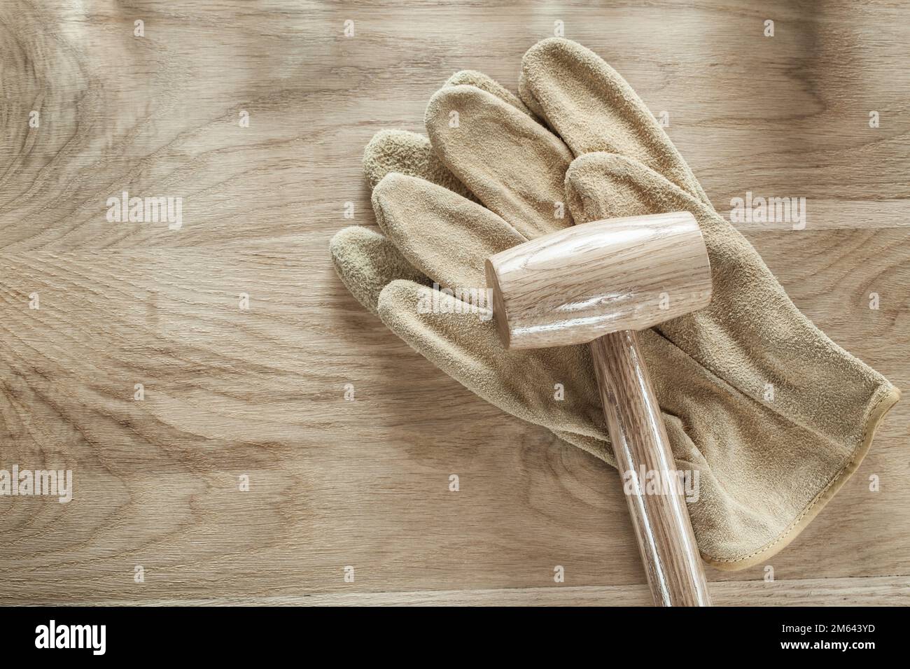 Leather protective gloves lump hammer on wooden board. Stock Photo