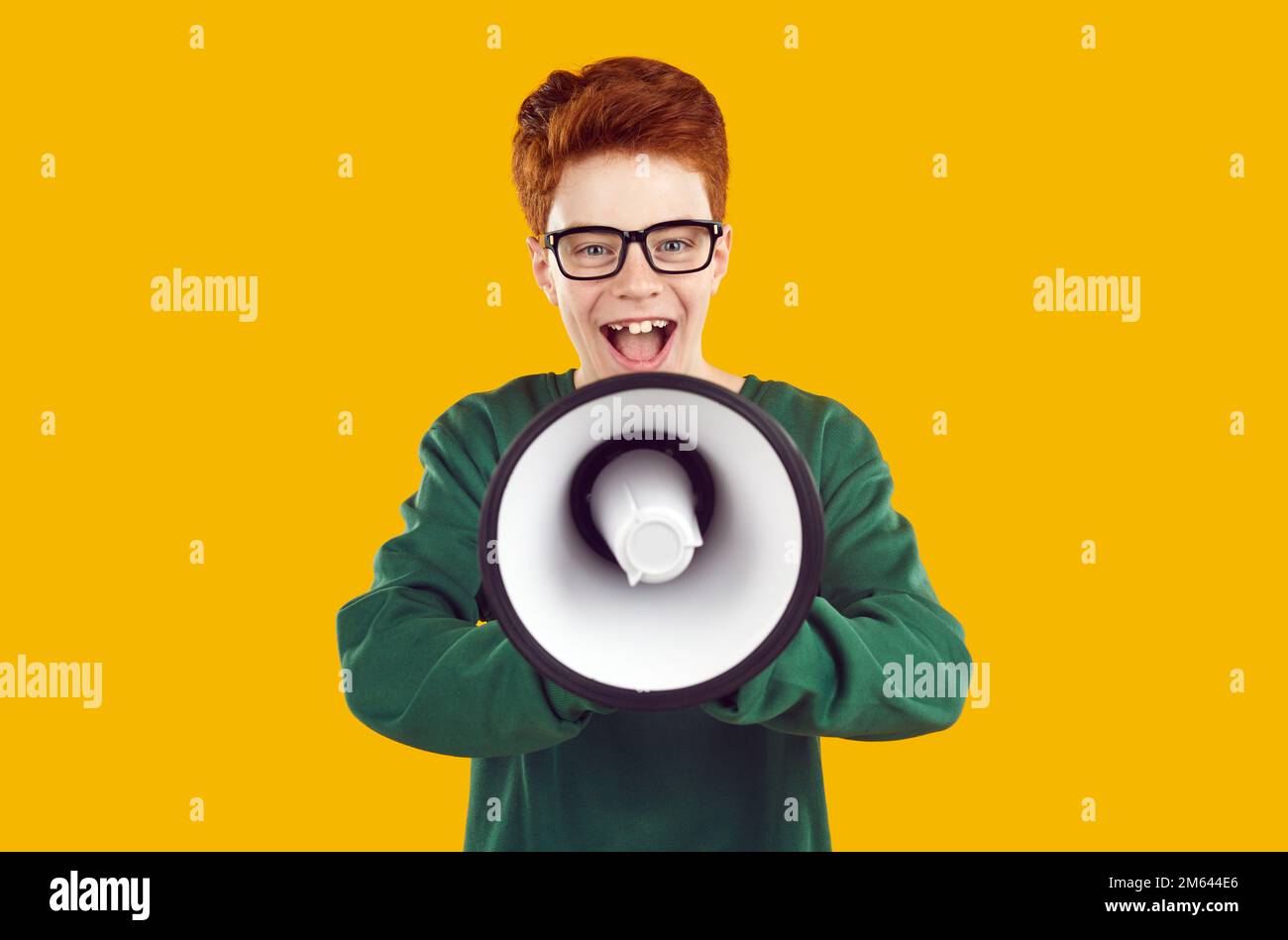 Portrait of happy teenage boy shouting into megaphone Stock Photo