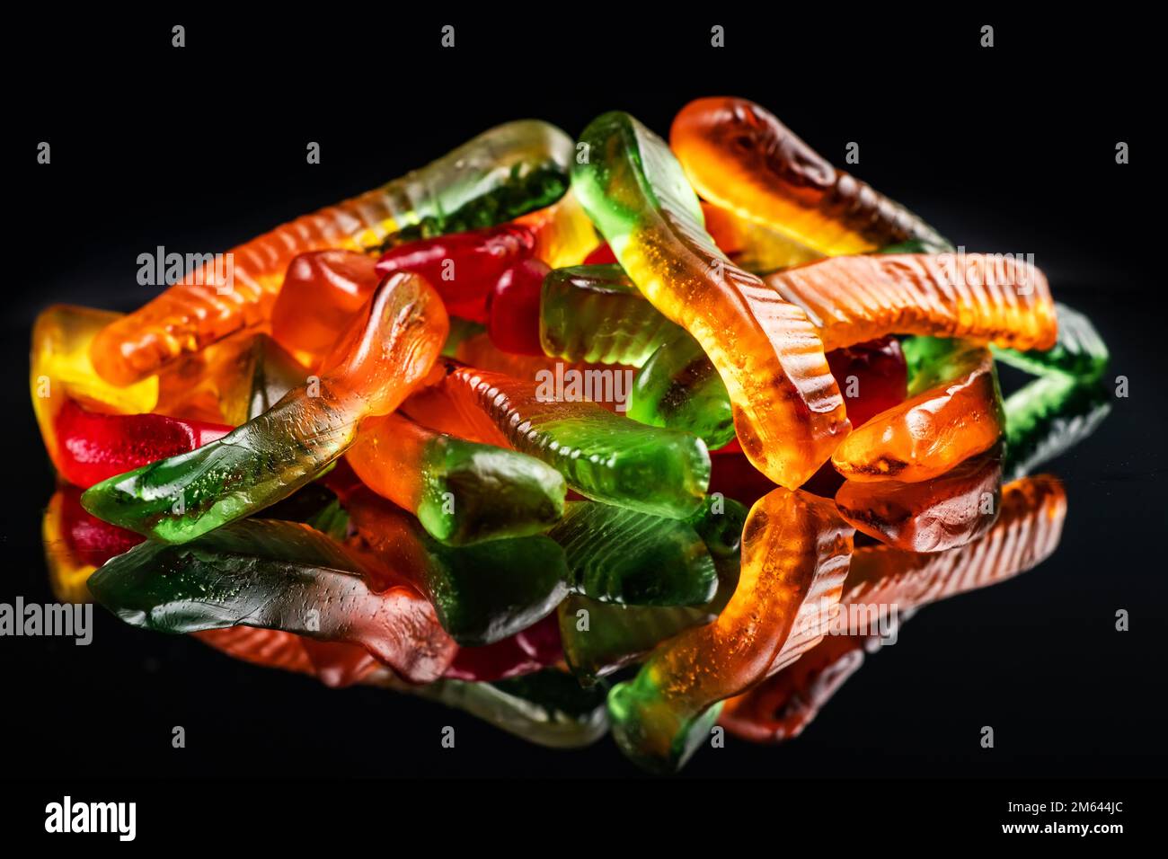 Heap juicy colorful jelly worms sweets. Gummy candies. Snakes. On black