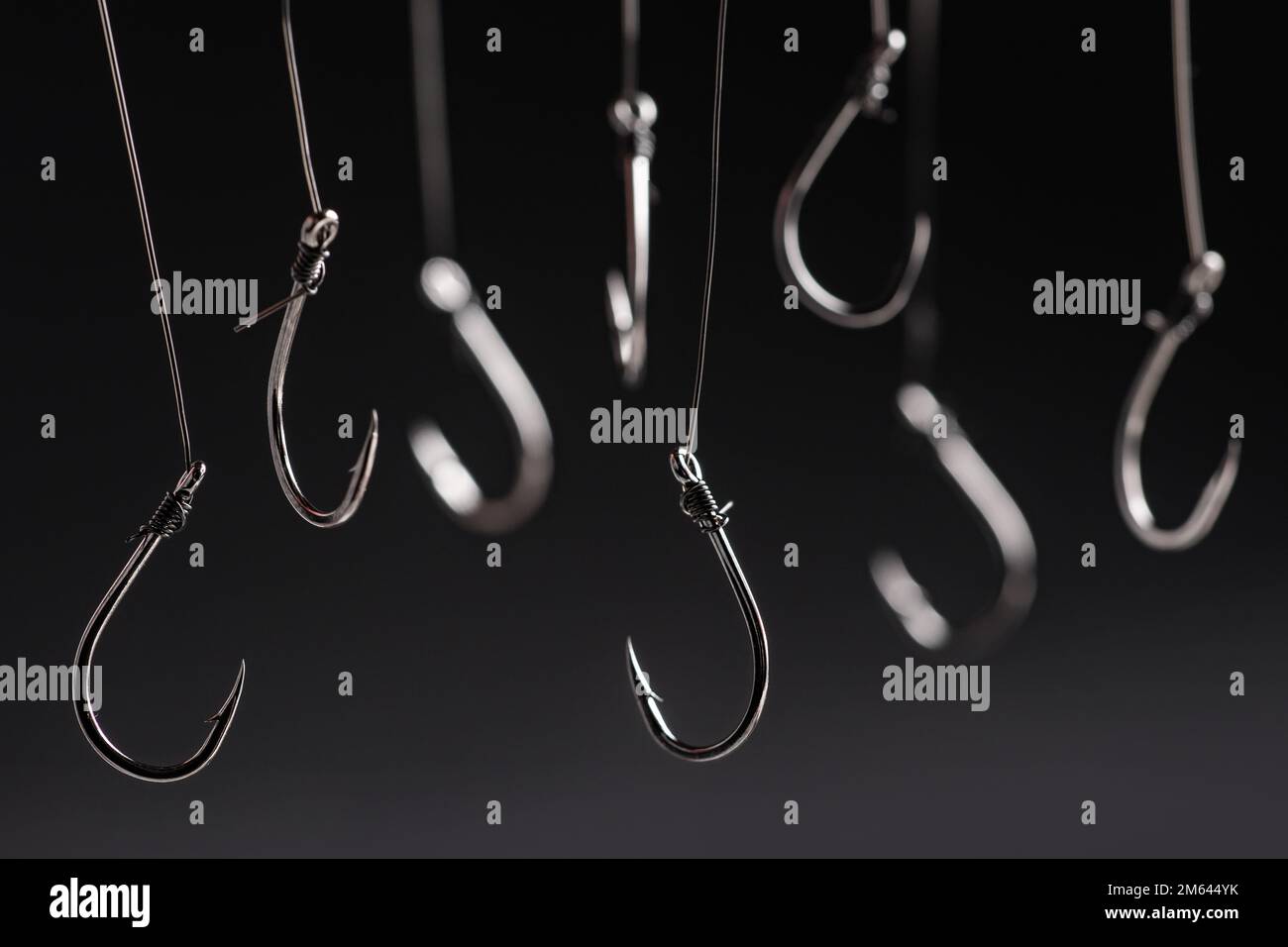 A fishing hooks hanging on a fishing line on a black background. Concept Stock Photo