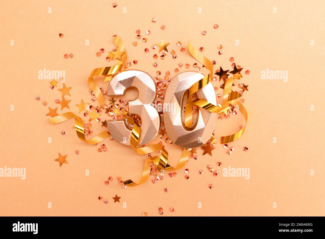 Gold colored number thirty, ribbons and stars confetti. Festive monochrome concept. Stock Photo