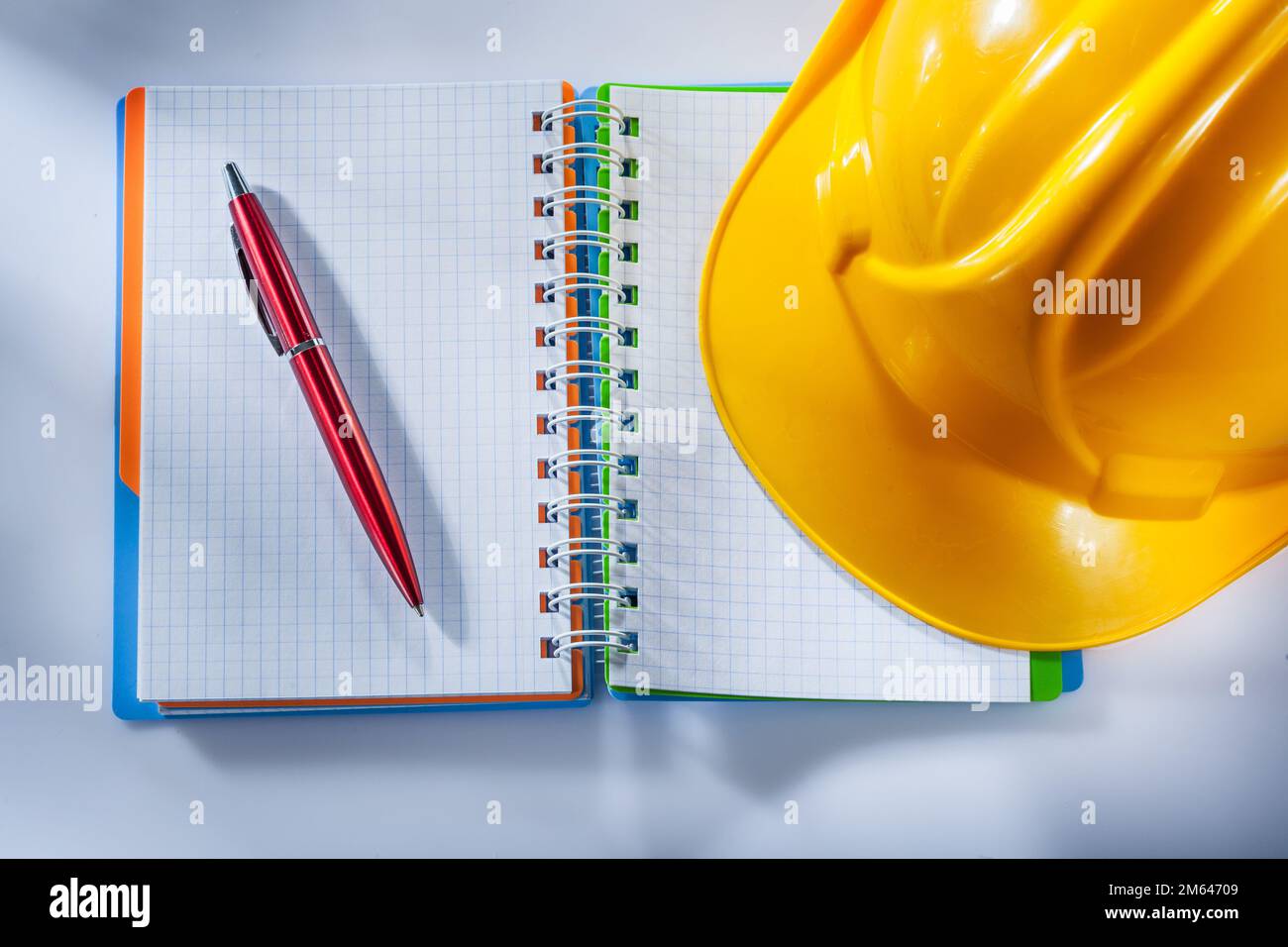 Safety hard hat checked notepad pen on white background. Stock Photo