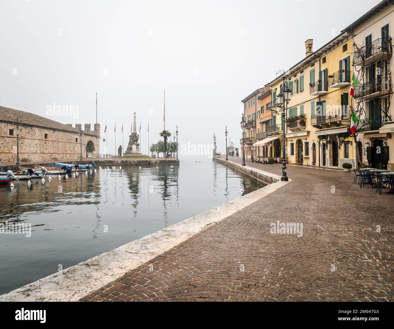 Old harbor of the small and picturesque town of Lazise on Lake Garda in the winter season. Lazise, Verona province, northern Italy - Europe Stock Photo