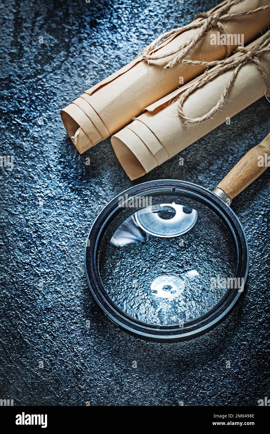 Vintage paper rolls magnifier on black surface Stock Photo - Alamy