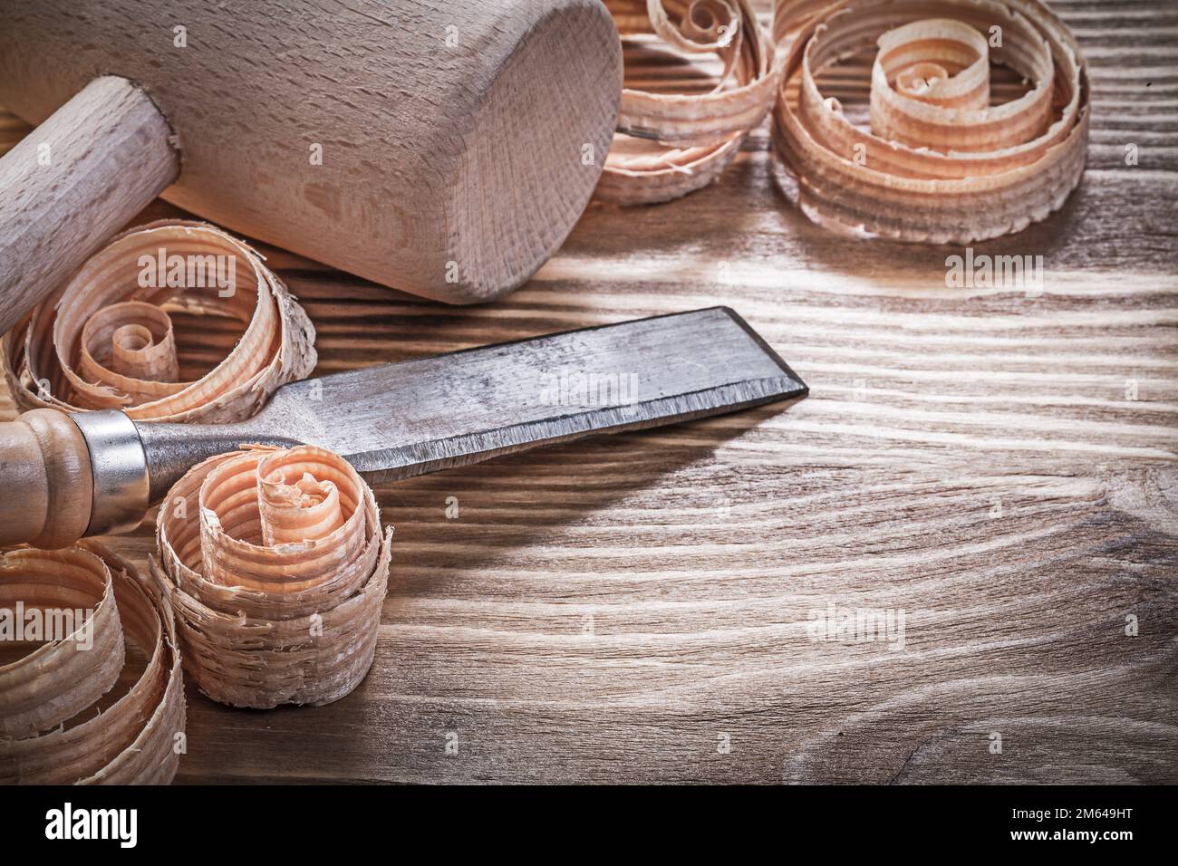 Wooden hammer firmer chisels curled shavings on vintage wood board construction concept. Stock Photo