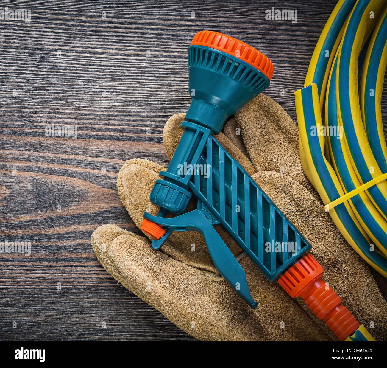 Twisted hand spraying garden rubber hose safety gloves on wooden board  agriculture concept Stock Photo - Alamy