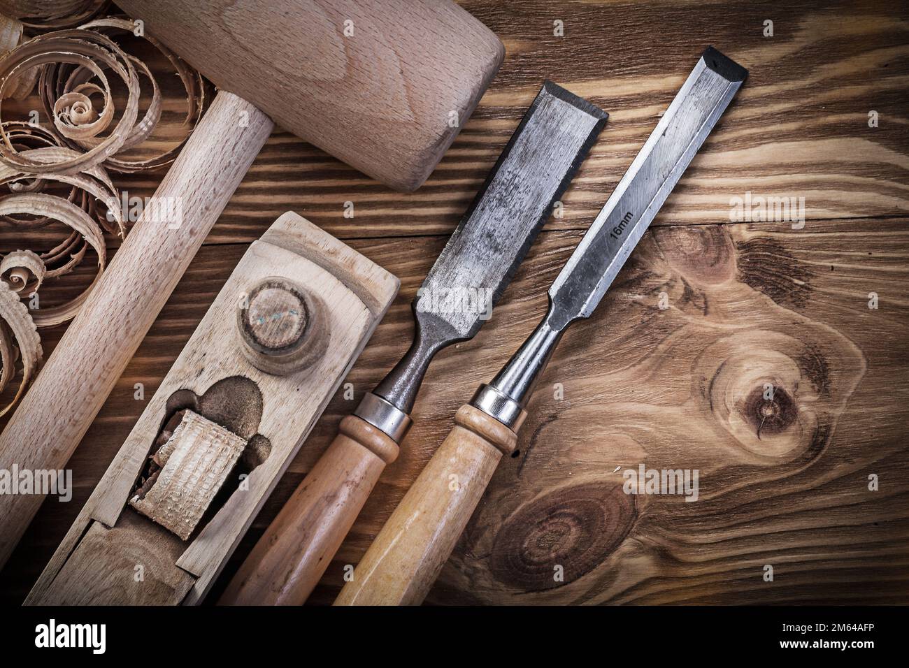 Wooden mallet shaving plane firmer chisels planning chips on vintage wood board construction concept. Stock Photo