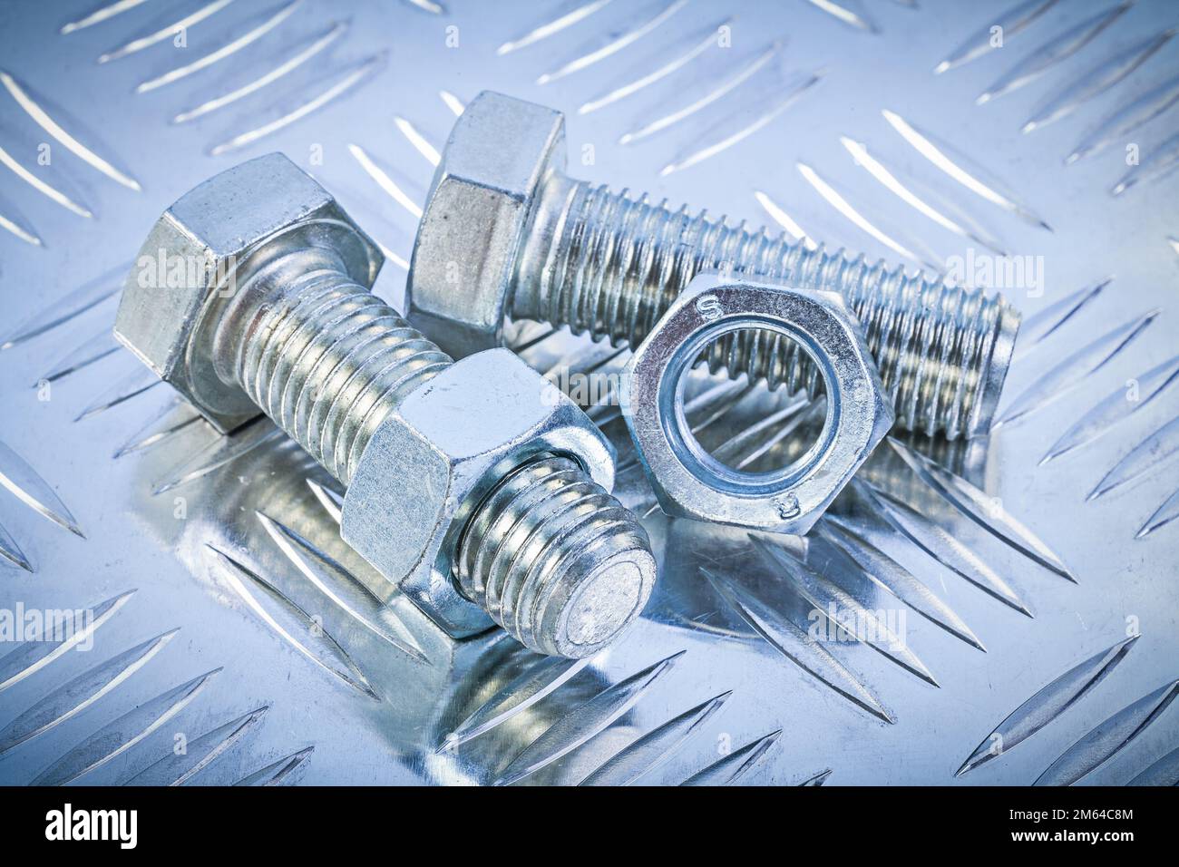 Stainless bolts and construction nuts on grooved metal sheet top view