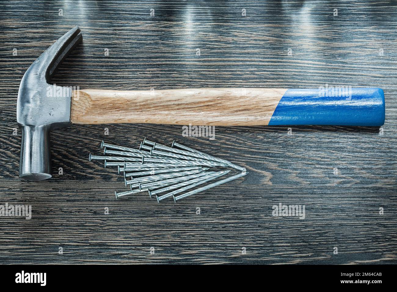 Stack of construction nails claw hammer on wooden board. Stock Photo