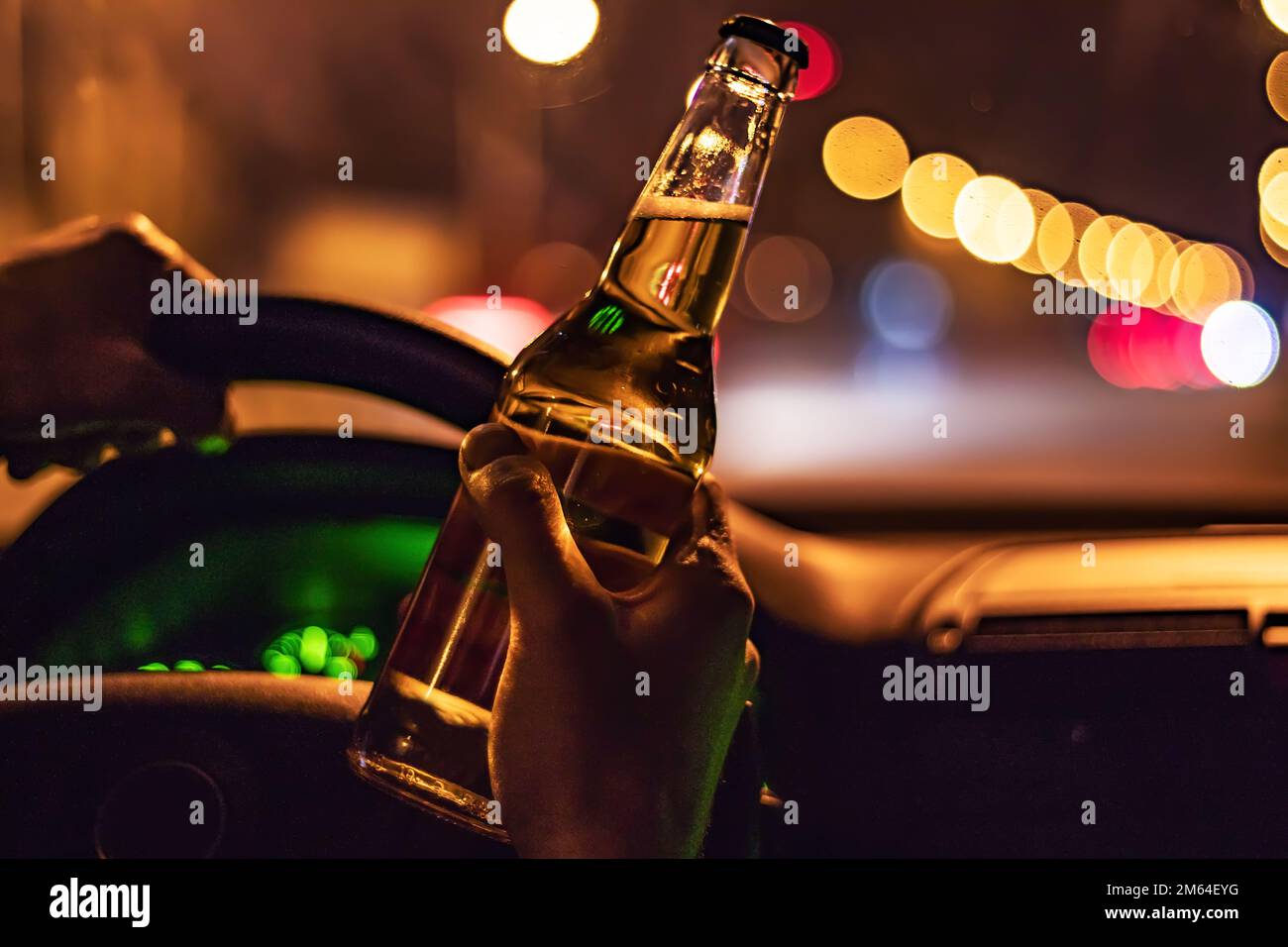 Man drink beer while driving at night in the city. Dangerously driving