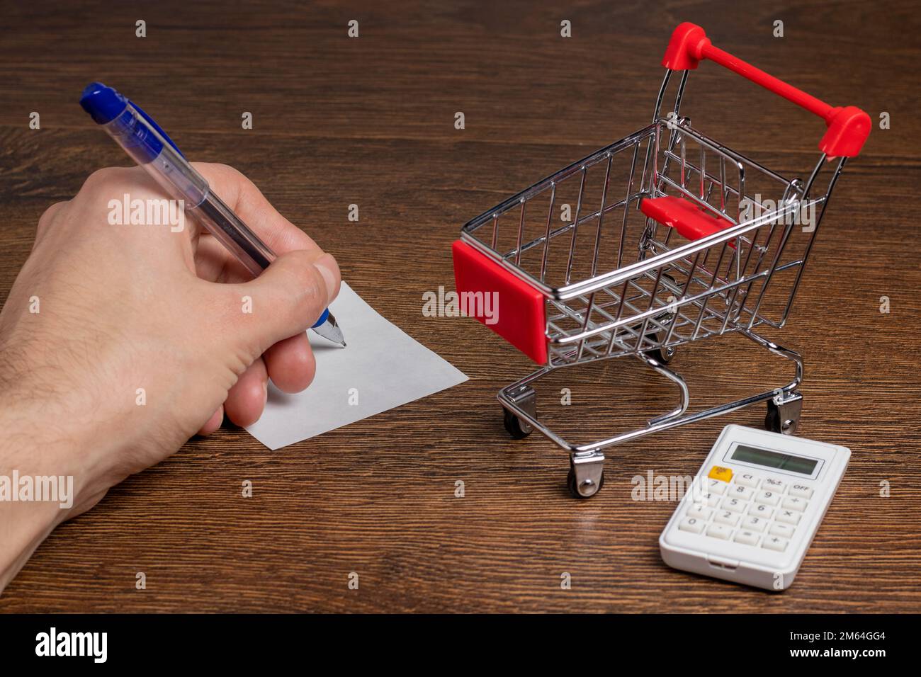 Man calculates the budget. Shopping cart a on table with calculator and