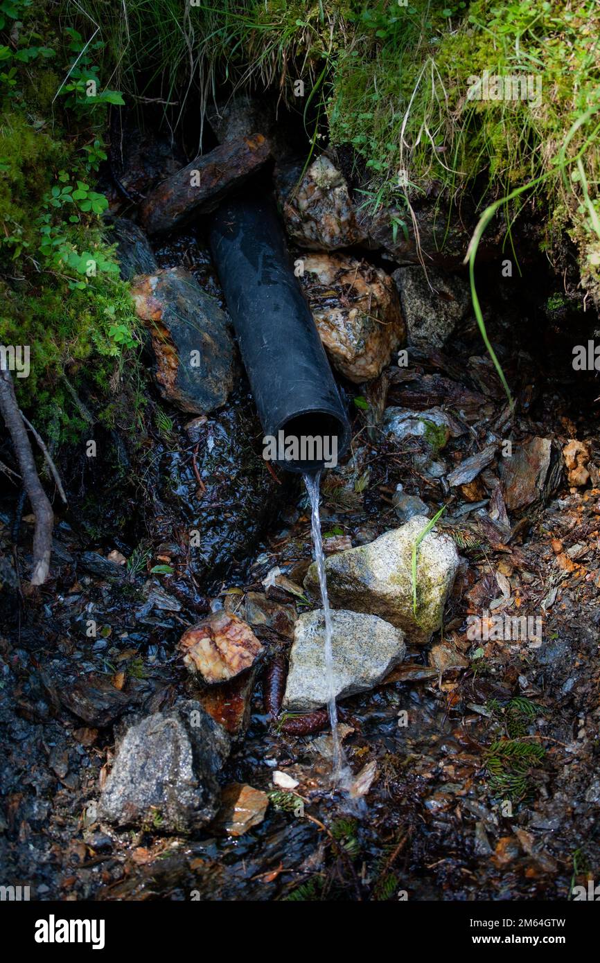 A water coming out from a black pipe Stock Photo