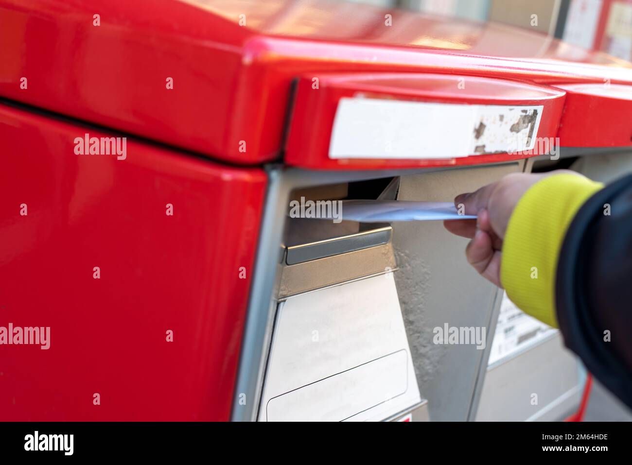 A hand dropping an envelope into a red post mail box Stock Photo