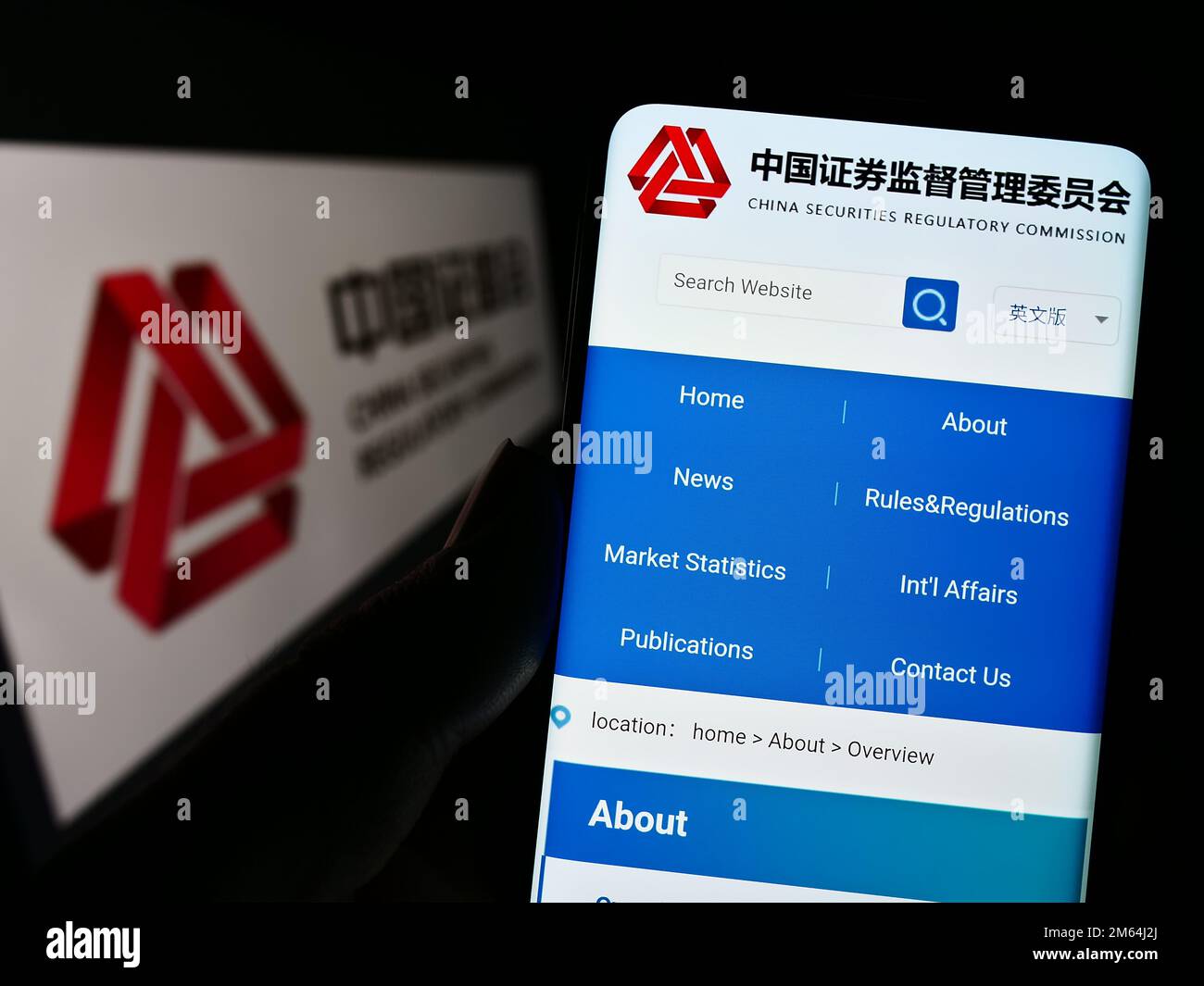 Person holding cellphone with website of China Securities Regulatory Commission (CSRC) on screen with logo. Focus on center of phone display. Stock Photo