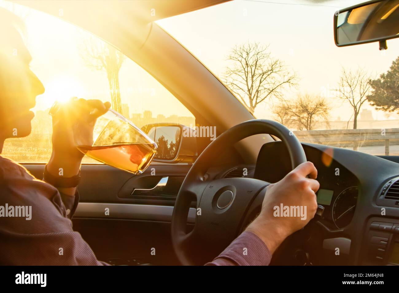 Man drinking alcohol while driving in his car on sunset Stock Photo - Alamy