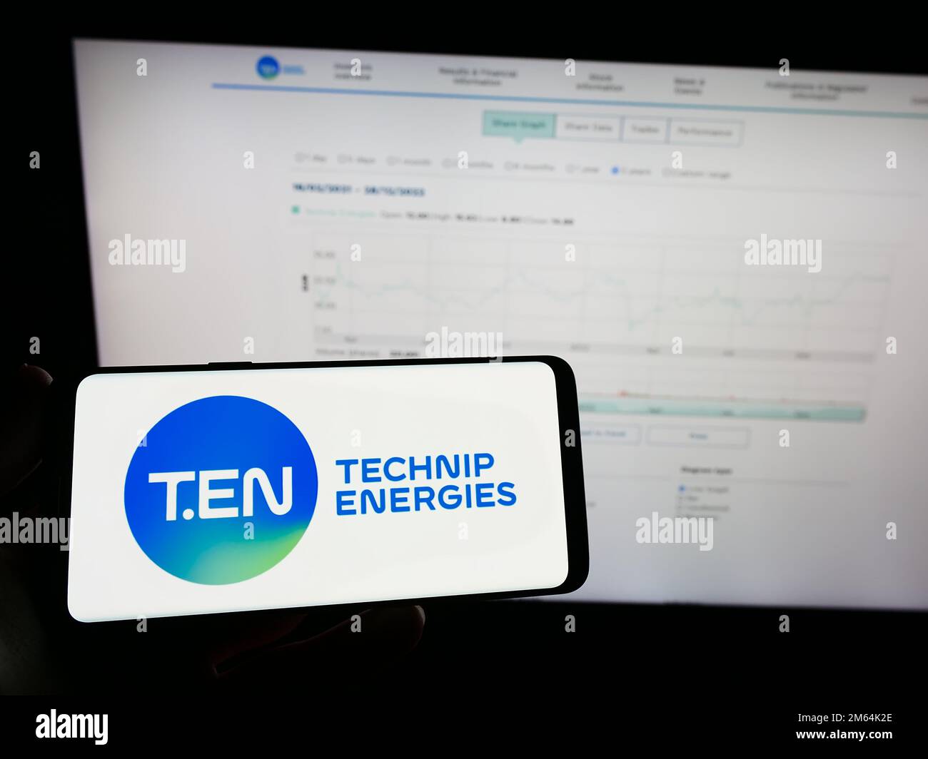 Person holding mobile phone with logo of French engineering company Technip Energies N.V. on screen in front of web page. Focus on phone display. Stock Photo