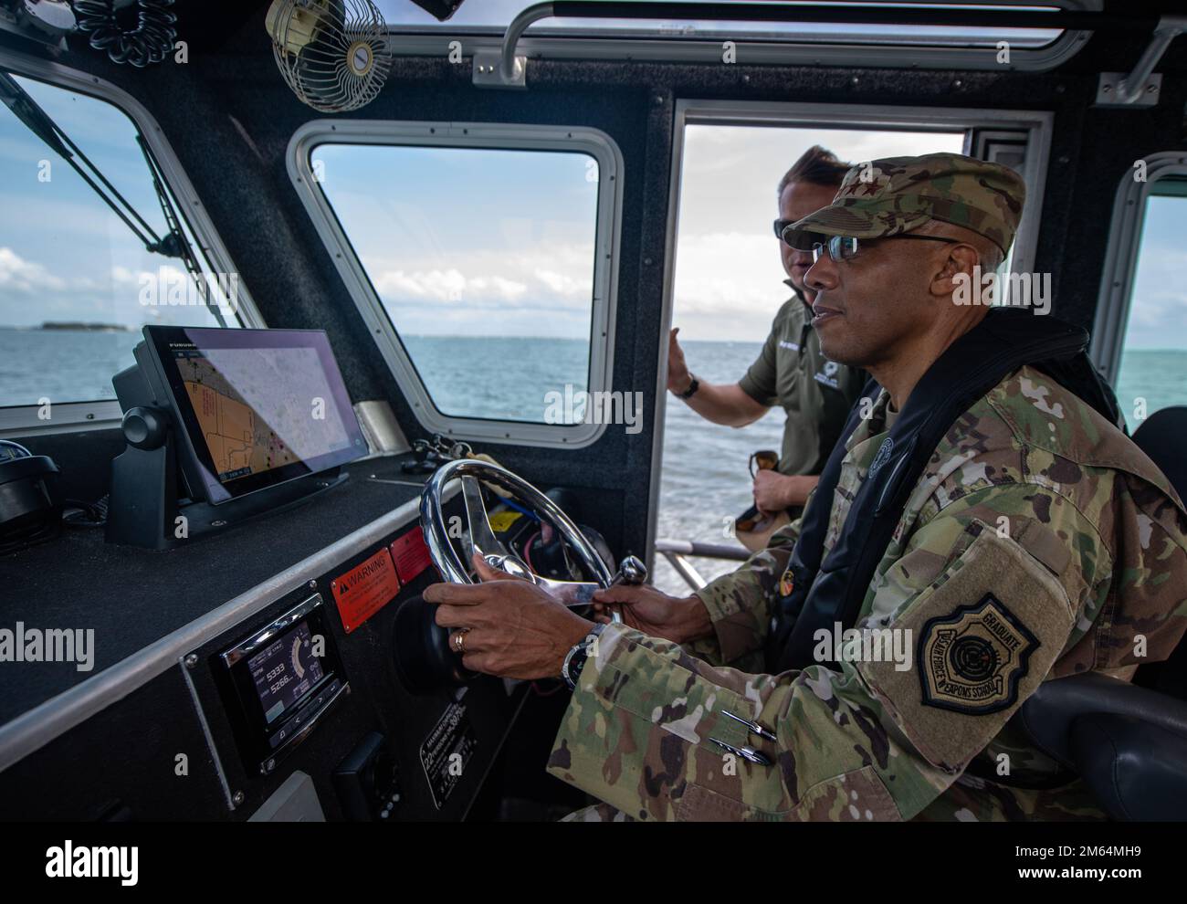 U.S. Air Force Chief of Staff Gen. CQ Brown, Jr. operates a marine patrol vessel assigned to the 6th Security Forces Squadron during a tour at MacDill Air Force Base, Florida, April 1, 2022. Gen. Brown visited the base to meet with Airmen and experience first-hand the innovative ways they're advancing the mission. Stock Photo