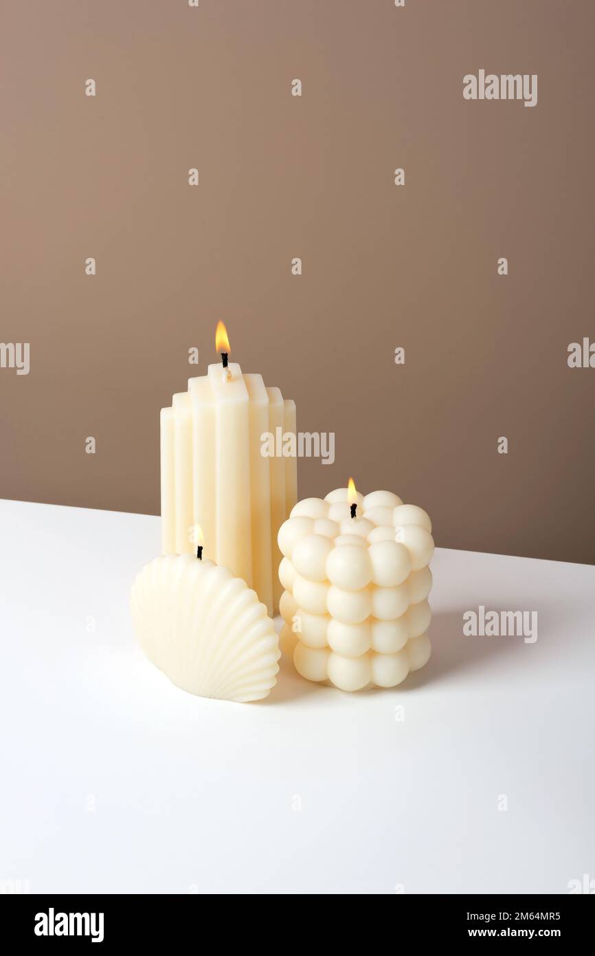 Olive wax burning candle on a duotone brown and white background. Sustainability vegan candle